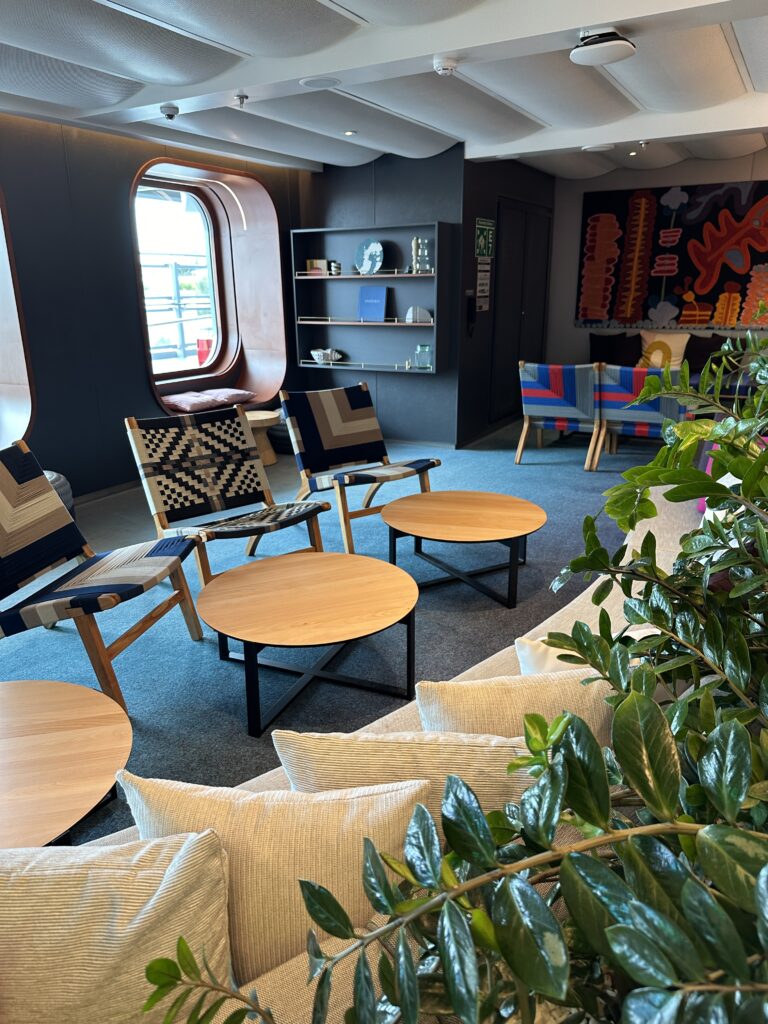 Modern lounge area aboard Virgin Voyages featuring stylish seating, designer furnishings, contemporary artwork and relaxing social spaces for sailors.