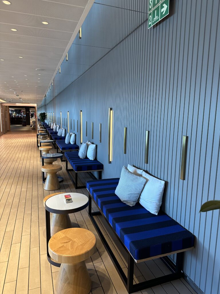 Stylish seating area aboard a Virgin Voyages cruise ship featuring contemporary blue seating, modern lighting and relaxing social spaces for sailors.