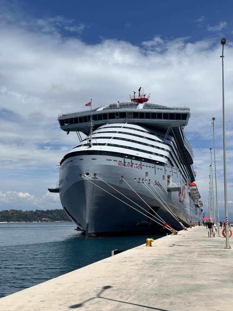 Front view of Virgin Voyages Resilient Lady docked alongside a cruise port showcasing the ship's distinctive modern design and adults-only cruise experience.