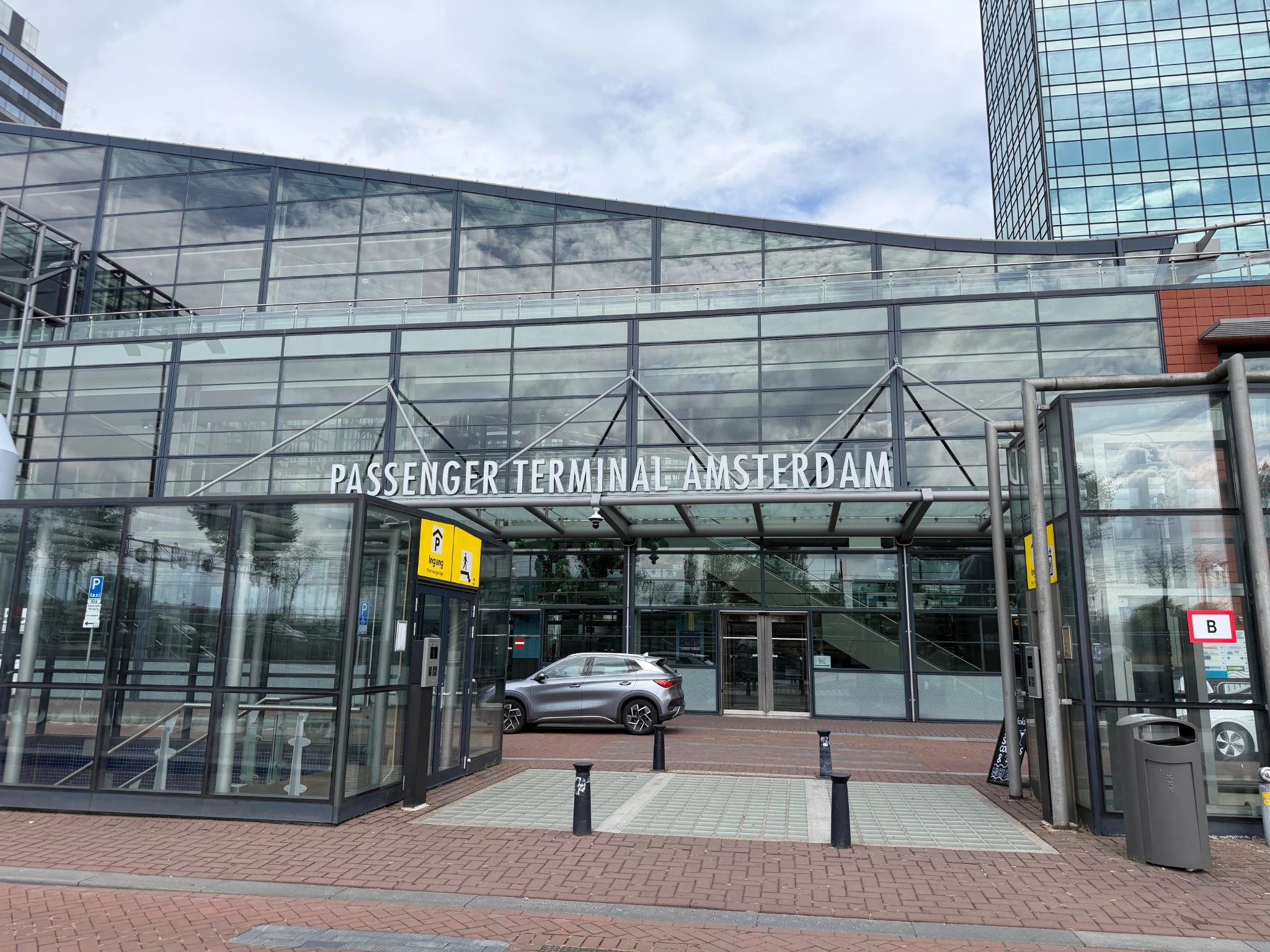 Entrance to Amsterdam Cruise Passenger Terminal with modern glass architecture on Amsterdam waterfront.