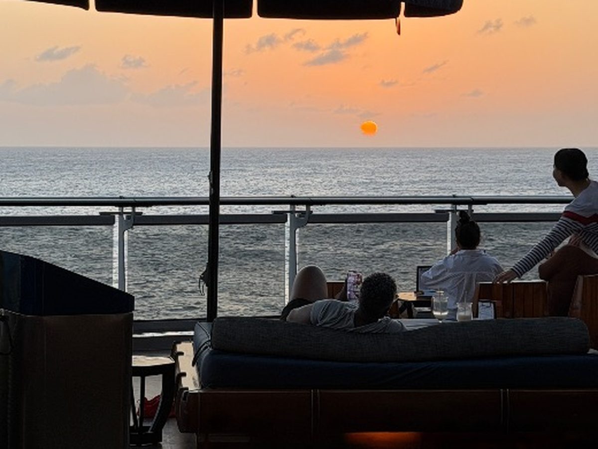 Guests relaxing on Valiant Lady while watching a sunset from the dock.